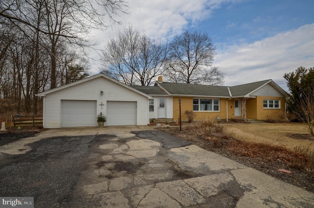 ranch-style home with driveway, fence, an attached garage, brick siding, and a chimney