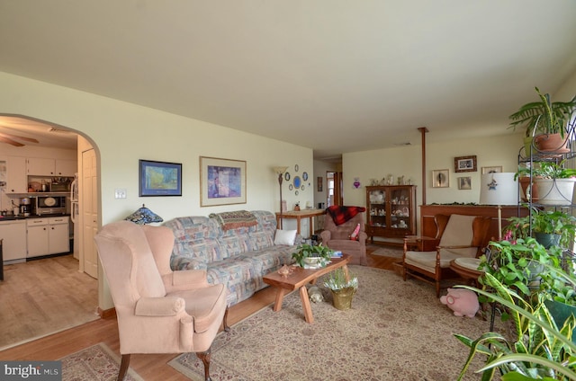 living area with arched walkways and light wood-style flooring