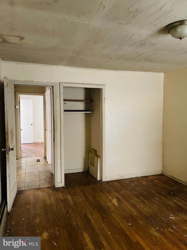 unfurnished bedroom with a closet and dark wood-style flooring