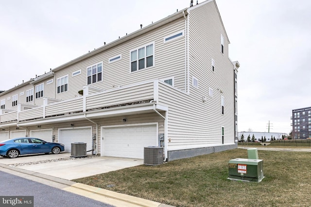 rear view of property with a yard, central AC unit, concrete driveway, and a garage