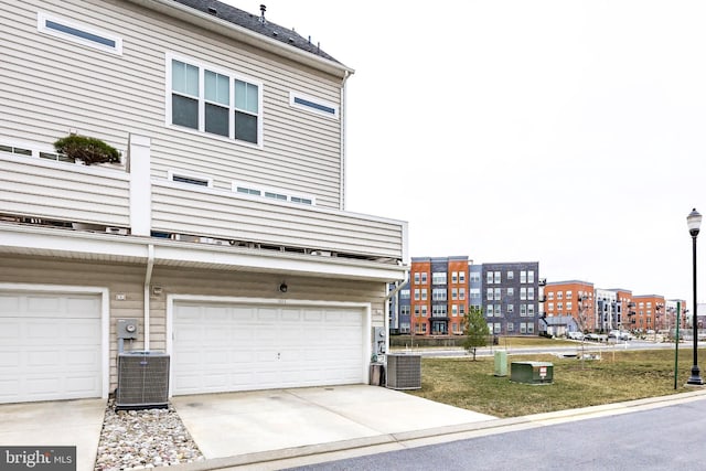 exterior space with central air condition unit, an attached garage, and concrete driveway