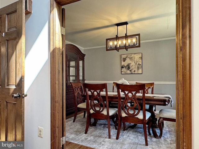 dining area featuring wood finished floors, an inviting chandelier, and ornamental molding