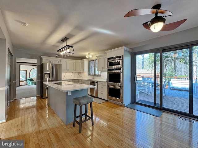 kitchen featuring a sink, a center island, white cabinetry, appliances with stainless steel finishes, and light countertops