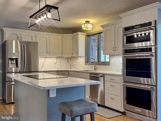 kitchen featuring a kitchen island, stainless steel appliances, light wood-type flooring, and a sink