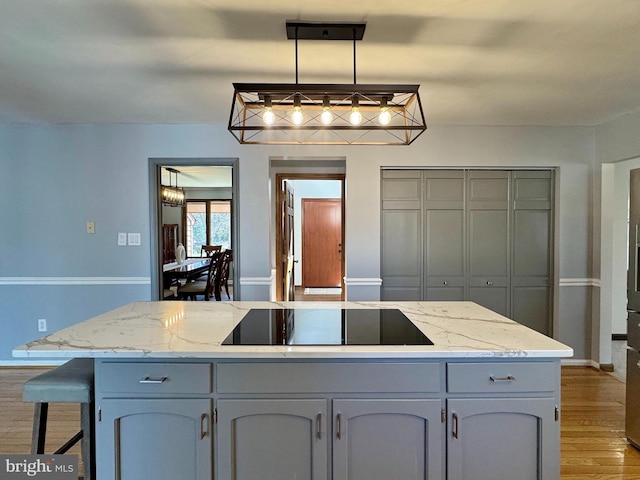 kitchen with black electric cooktop, light stone countertops, light wood-style floors, and gray cabinetry