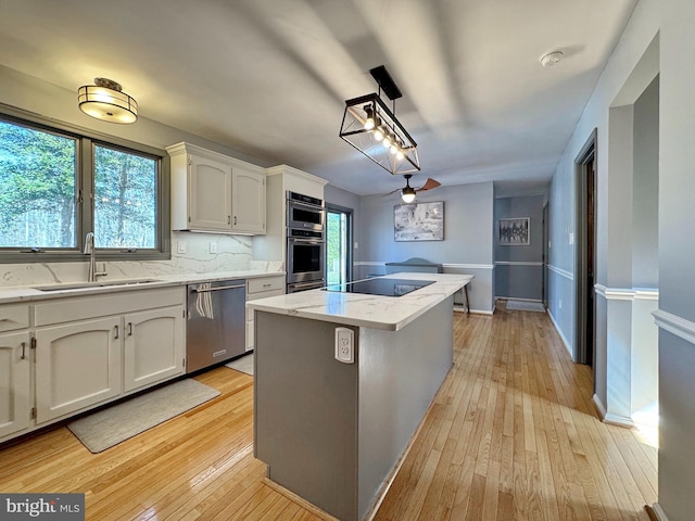 kitchen featuring a sink, stainless steel appliances, a kitchen island, and light wood-style flooring