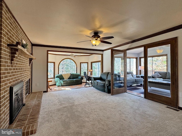 unfurnished living room featuring a brick fireplace, ornamental molding, a wealth of natural light, and ceiling fan