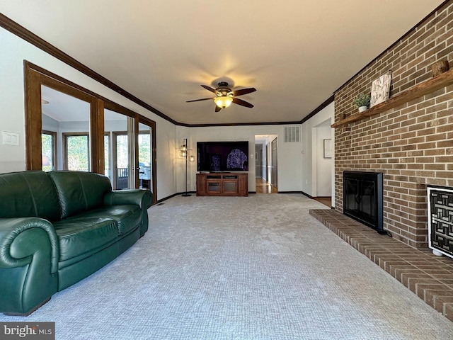 carpeted living room with visible vents, a brick fireplace, crown molding, baseboards, and a ceiling fan