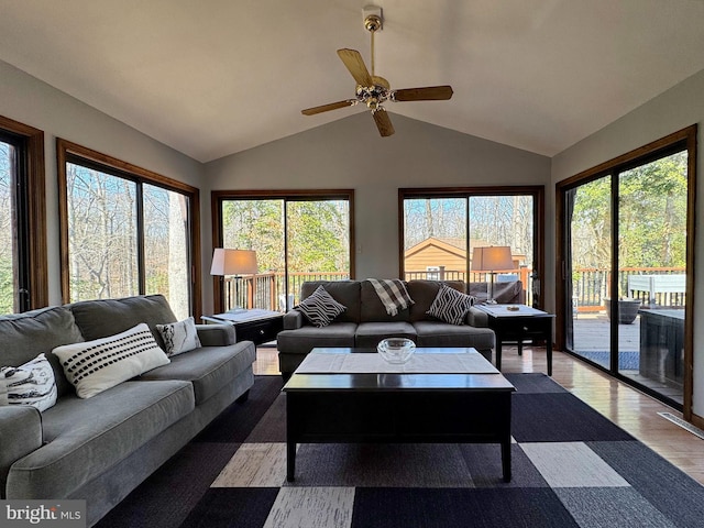 living area with plenty of natural light, lofted ceiling, a ceiling fan, and wood finished floors