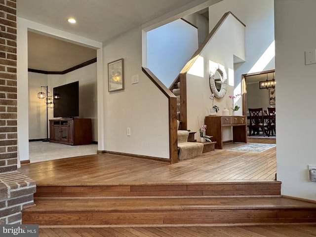 staircase featuring baseboards, an inviting chandelier, and hardwood / wood-style flooring