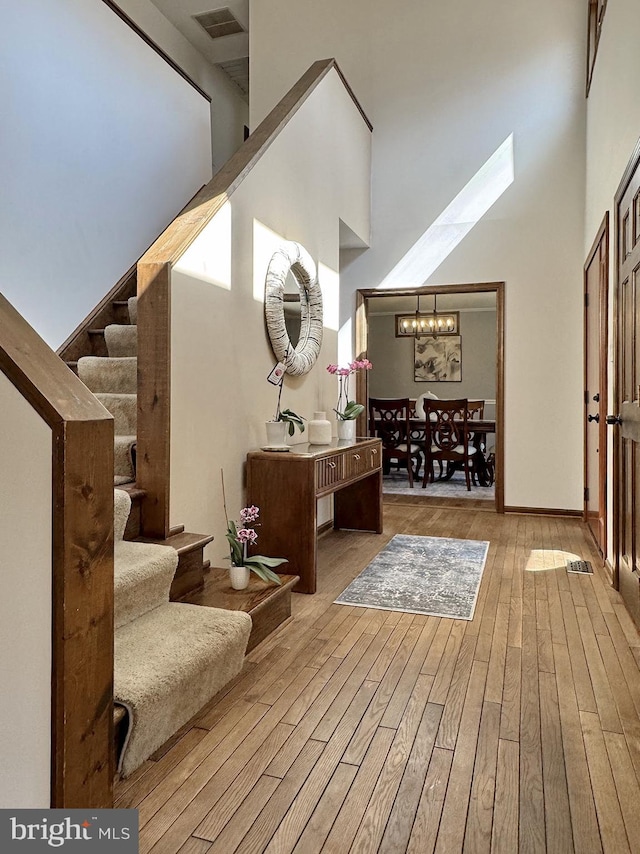 interior space featuring stairway, a skylight, a towering ceiling, and wood finished floors