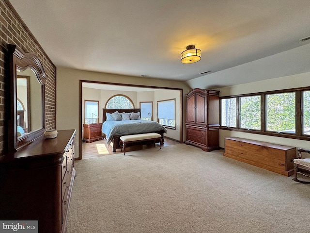 bedroom featuring visible vents, light colored carpet, and vaulted ceiling