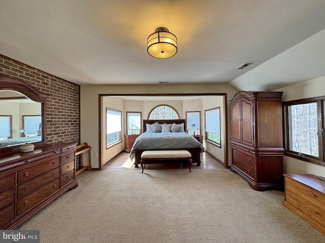 bedroom featuring baseboards, visible vents, brick wall, and light carpet