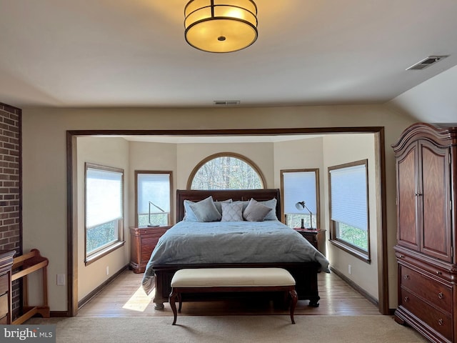 bedroom with visible vents, light wood-style floors, and baseboards