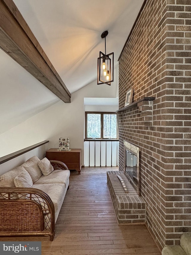 living area with lofted ceiling with beams, an inviting chandelier, hardwood / wood-style floors, and a fireplace