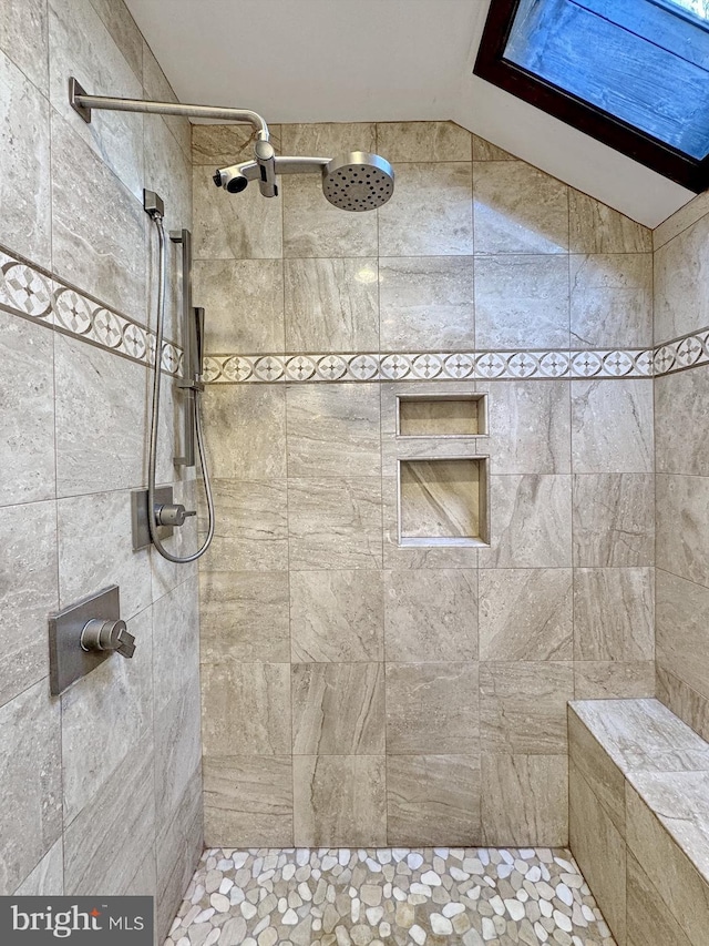 full bathroom with a tile shower and vaulted ceiling