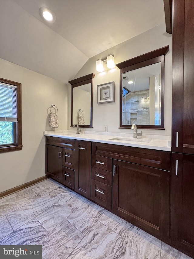 full bathroom featuring lofted ceiling, double vanity, baseboards, and a sink