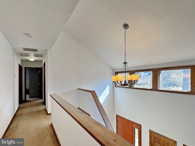 corridor with baseboards, visible vents, light carpet, a notable chandelier, and an upstairs landing