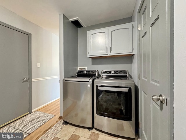 laundry area with light wood-type flooring, baseboards, cabinet space, and washer and clothes dryer