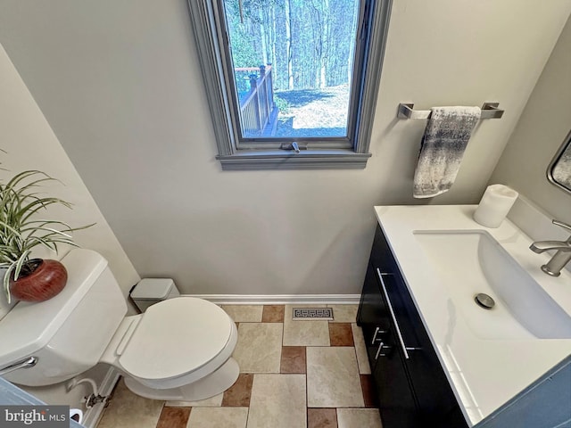 half bathroom with visible vents, toilet, vanity, and baseboards