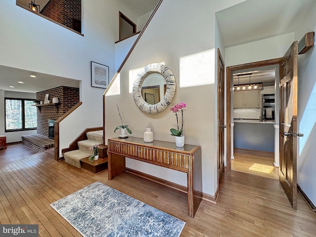 interior space with a fireplace, a high ceiling, baseboards, and wood-type flooring