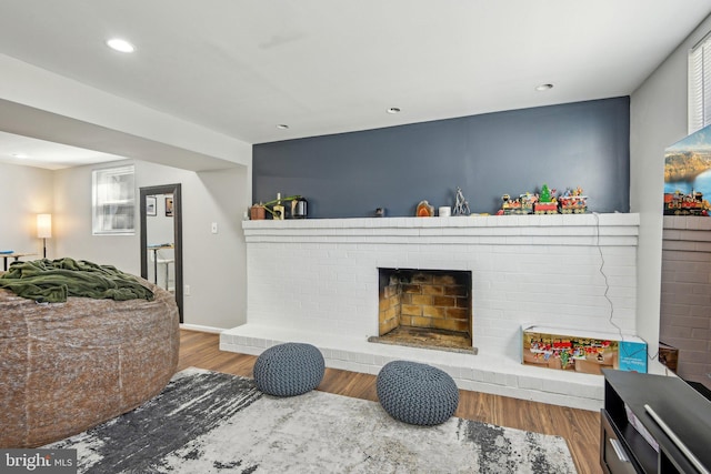 interior space featuring recessed lighting, a fireplace, baseboards, and wood finished floors