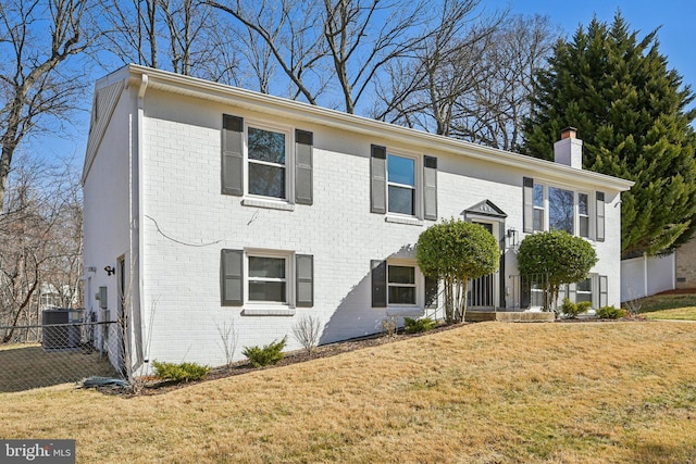 bi-level home featuring a front lawn, fence, brick siding, central AC unit, and a chimney