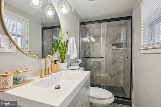 bathroom featuring visible vents, a shower stall, toilet, and vanity