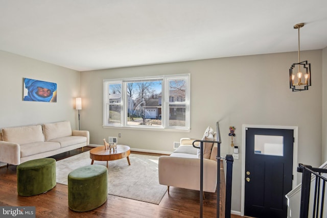 living room with a chandelier, baseboards, visible vents, and wood finished floors