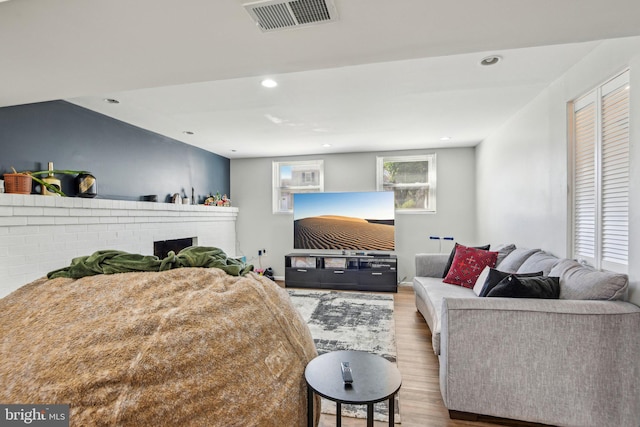 bedroom with a fireplace, recessed lighting, wood finished floors, and visible vents