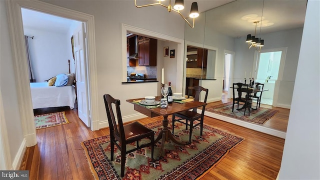 dining space with baseboards, an inviting chandelier, and wood-type flooring