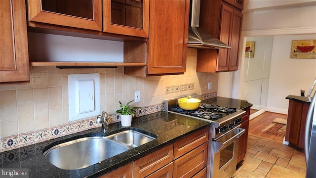 kitchen with a sink, tasteful backsplash, brown cabinetry, extractor fan, and high end range