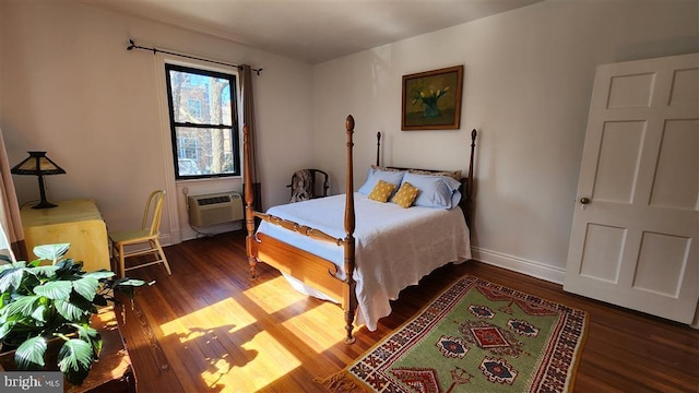 bedroom featuring baseboards, an AC wall unit, and wood finished floors