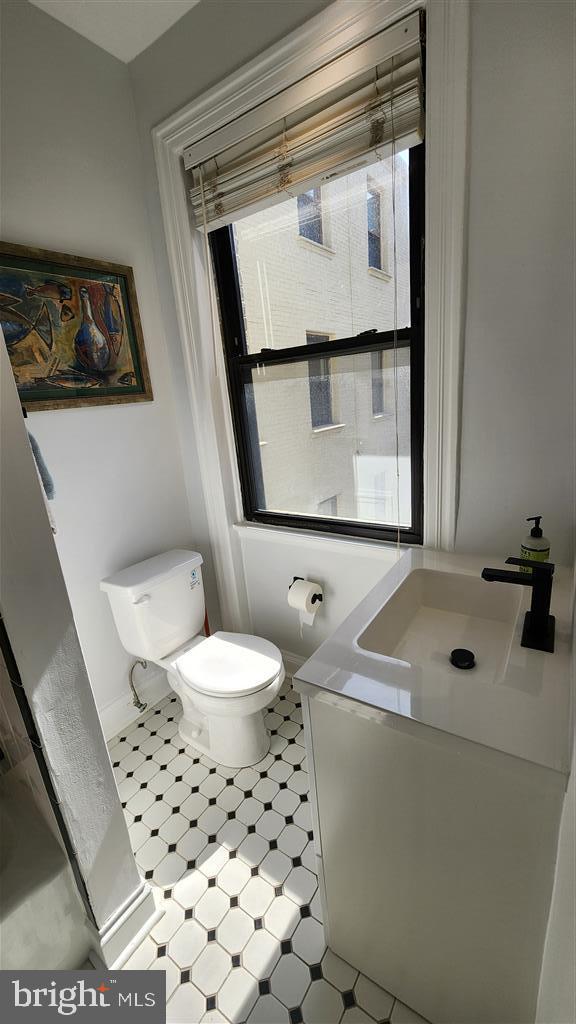 half bathroom with tile patterned floors, toilet, and vanity