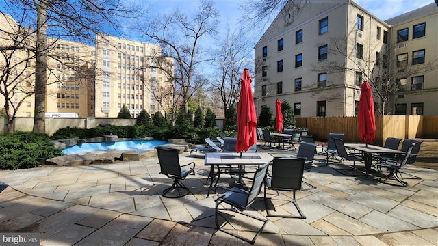 view of patio / terrace featuring a community pool, outdoor dining space, and fence