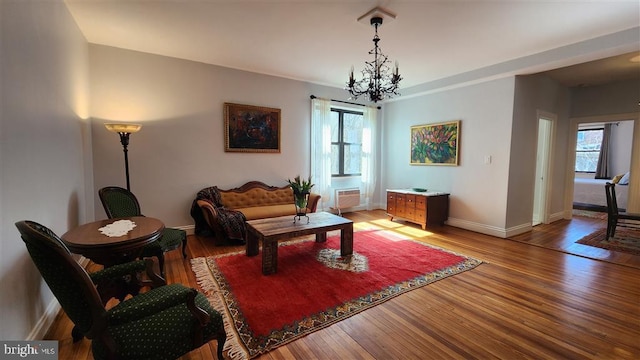 living area featuring baseboards, a notable chandelier, and light wood finished floors