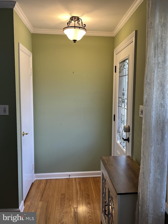 foyer entrance featuring crown molding, plenty of natural light, wood finished floors, and baseboards