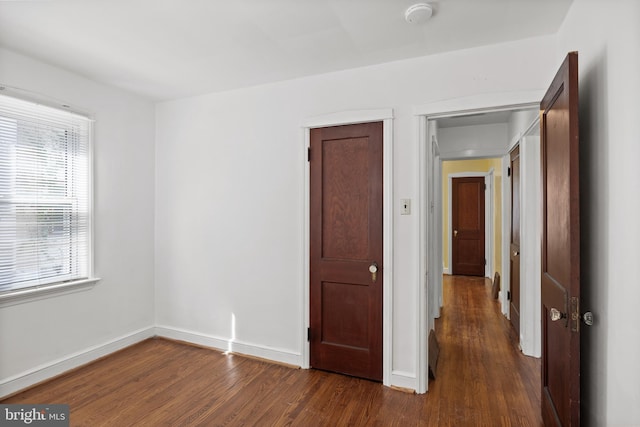 unfurnished room with wood finished floors, plenty of natural light, baseboards, and a smoke detector