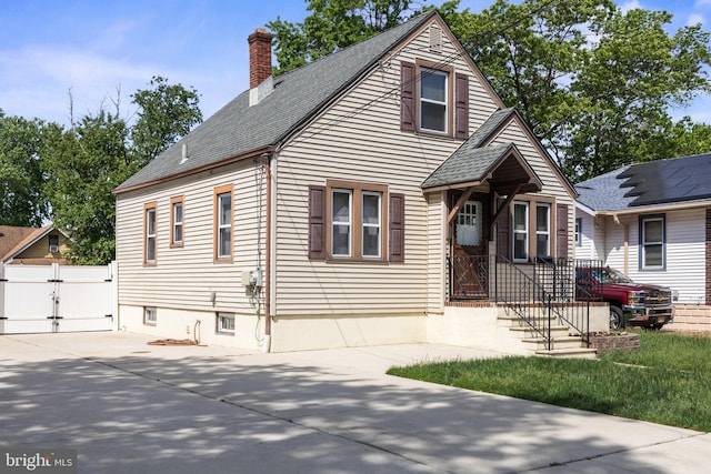 view of front facade featuring a gate, a shingled roof, a chimney, concrete driveway, and fence