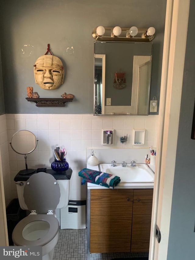 bathroom with tile patterned floors, toilet, vanity, and tile walls