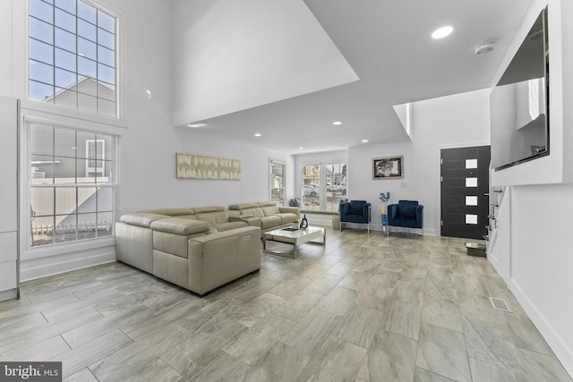 living room featuring visible vents, recessed lighting, baseboards, and a towering ceiling