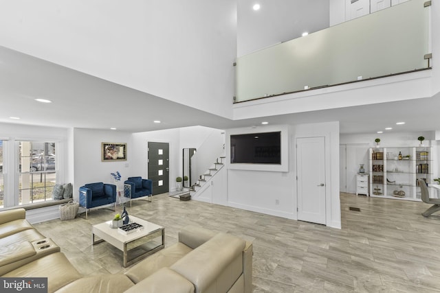 living room featuring stairway, recessed lighting, and a towering ceiling