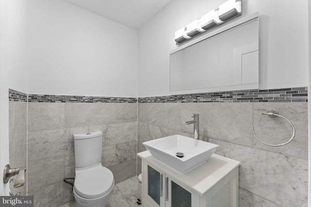 half bathroom featuring toilet, marble finish floor, and vanity