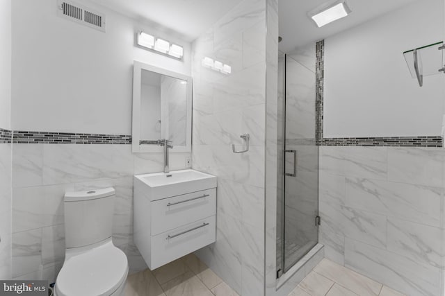 bathroom with visible vents, toilet, tile walls, a shower stall, and vanity