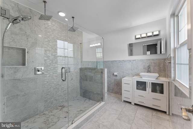 full bathroom with wainscoting, a shower stall, vanity, and tile walls