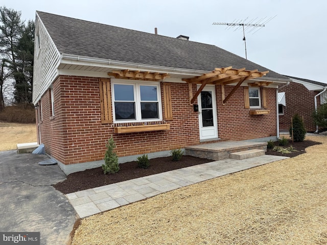 view of front of home with brick siding and a shingled roof