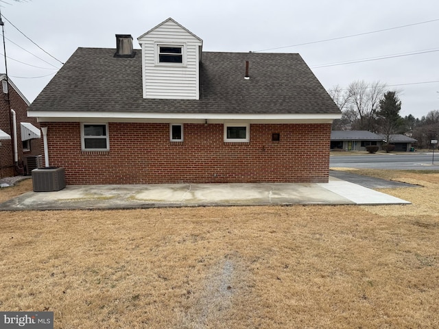 back of house featuring a yard, brick siding, and a shingled roof