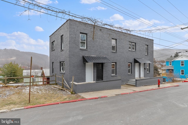 view of front of home featuring brick siding, a mountain view, and fence