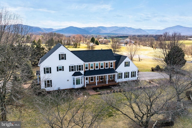 rear view of house featuring roof with shingles and a deck with mountain view