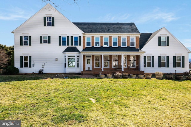 view of front of house featuring a front lawn, covered porch, and brick siding